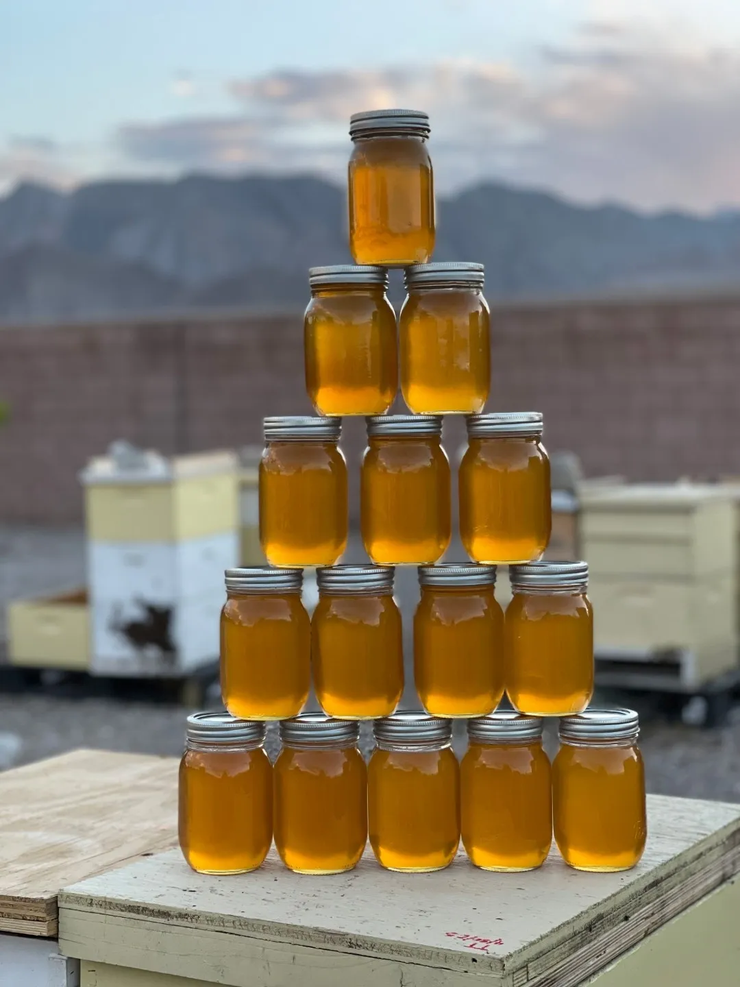 Jars of Wright's honey stacked in a pyramid on a hive box